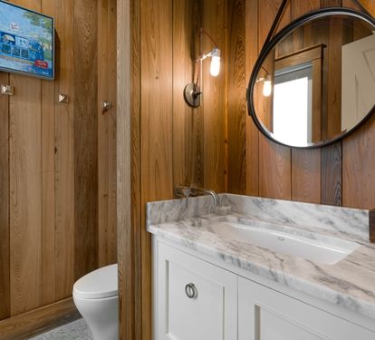 Unwind in your elegant bathroom featuring warm wood walls, marble countertops, and modern fixtures for your comfort.