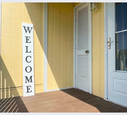 Bright yellow building entrance with welcoming white door and covered porch area for guest arrivals.