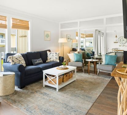 Sink into your spacious living room where coastal charm meets comfort—plush seating, warm wood accents, and abundant natural light create your perfect retreat.
