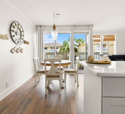 Your bright, open living space flows seamlessly from kitchen to dining, with palm trees swaying beyond your private balcony doors.