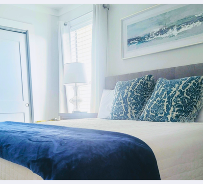 Drift off to sleep surrounded by soothing coastal blues and crisp white linens, where ocean-inspired artwork sets the perfect serene mood.