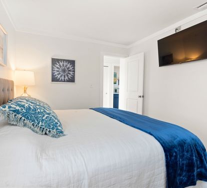 Your serene bedroom awaits with a plush tufted headboard, crisp linens, and soothing blue accents. Unwind while watching your favorite shows on the wall-mounted TV.