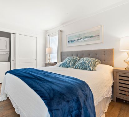 Sink into the plush tufted headboard and crisp linens, where coastal artwork and warm lighting create your perfect retreat.