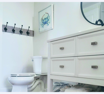 Your bright bathroom features coastal charm with a vanity offering ample storage and convenient wall hooks for your belongings.