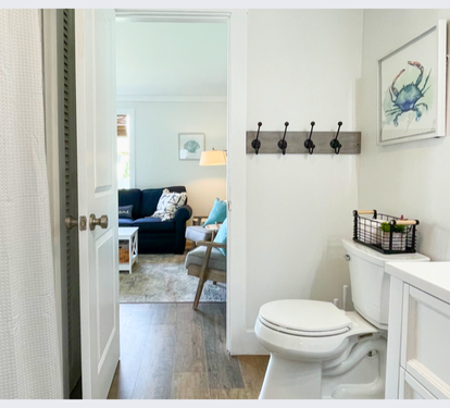 Your private powder room features coastal charm with thoughtful hooks and storage, connecting seamlessly to the bright living space.