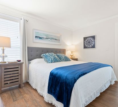 Sink into crisp white linens and ocean-inspired blue accents in your peaceful bedroom retreat, where coastal artwork creates a serene escape.