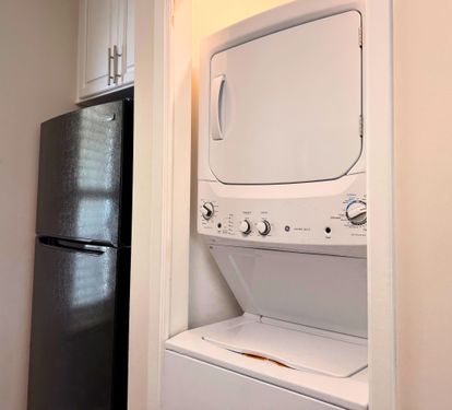 A stacked washer-dryer unit nestles conveniently in the kitchen alcove, with a sleek refrigerator nearby—so you can keep essentials close and your wardrobe fresh throughout your stay.