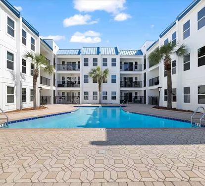 Beautiful resort-style courtyard pool surrounded by palms and lounge seating—your private oasis near the beach.