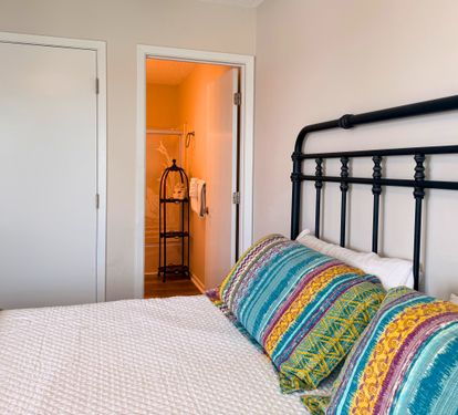 Settle into this charming primary bedroom with vibrant bedding and a cheerful wardrobe space just steps away—your cozy home base awaits.