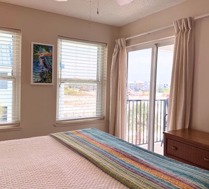 Bright, beachy primary bedroom featuring colorful tropical artwork and stunning water views from your private balcony. Relax in comfort with thoughtful furnishings and natural light.