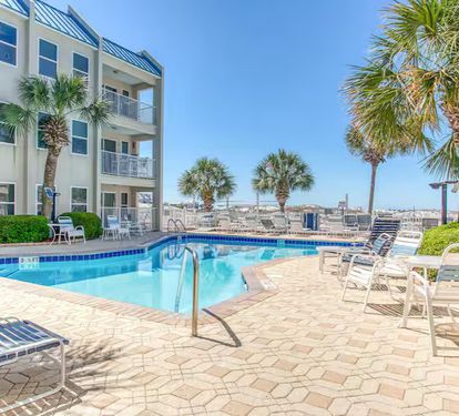 Beachfront pool with Gulf views, palm-lined deck, and plenty of loungers—relax just steps from the sand.