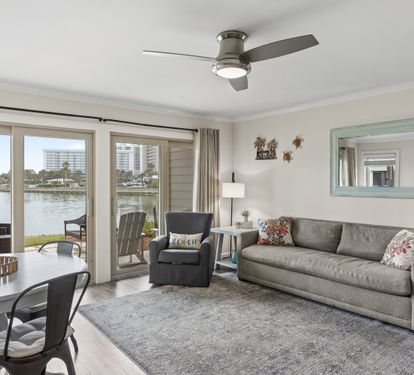 Relax in your waterfront living room with panoramic windows framing stunning lake views and comfortable seating for peaceful evenings.