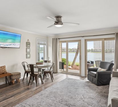 Relax in your spacious waterfront living room with stunning lake views through floor-to-ceiling windows. Comfortable seating and dining area await your arrival.