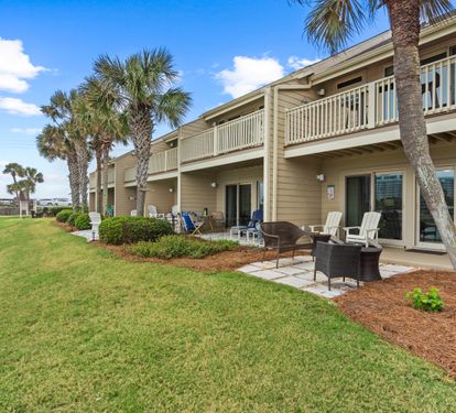 Beachfront property featuring palm trees and expansive lawn areas with private patios for guest units.