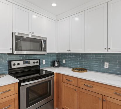 Step into your fully equipped kitchen featuring sleek two-tone cabinetry, modern stainless appliances, and elegant subway tile backsplash.
