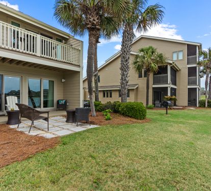 Relax on your private patio with outdoor seating while enjoying peaceful lake views through towering palm trees.