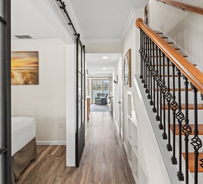 Step into your elegant hallway where warm wood floors guide you past stylish artwork toward inviting living spaces upstairs.