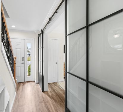 Step into your bright, modern entryway with sleek glass barn doors and warm hardwood floors welcoming you home.
