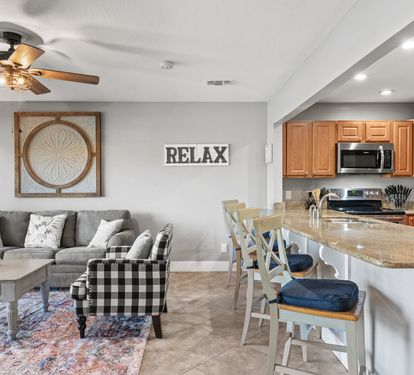 Open-concept living and kitchen area with coastal décor, bar seating, and plenty of space to relax after a beach day.