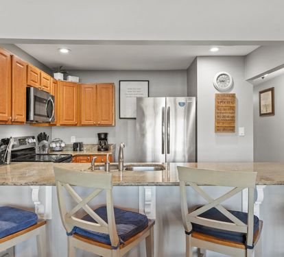 Fully equipped kitchen with stainless appliances, granite countertops, and bar seating for casual dining and conversation.