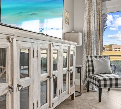 Coastal-inspired living space with stylish décor, a large flatscreen TV, comfortable seating, and peaceful lake views.