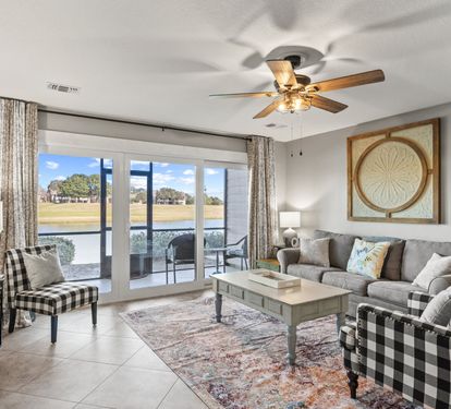 Bright coastal living area with comfortable seating, peaceful lake views, and direct patio access for relaxing mornings and sunsets.