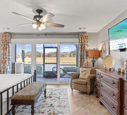 Relax in the spacious primary suite with cozy seating, peaceful lake views, and direct access to the private patio.
