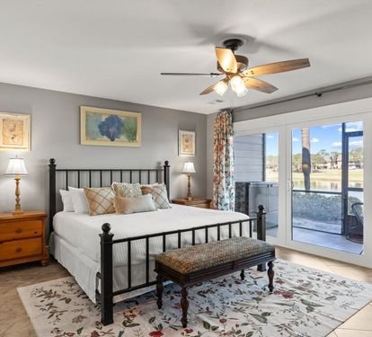 Spacious primary bedroom with a king bed, cozy coastal décor, and direct patio access with peaceful lake views.