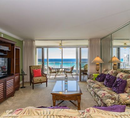 Relax in your bright living room with tropical decor and stunning ocean views through floor-to-ceiling windows opening to your private balcony.