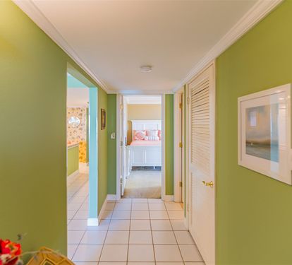 Bright hallway connects your space with cheerful green walls, tropical art, and fresh flowers creating a welcoming tropical atmosphere throughout your stay.