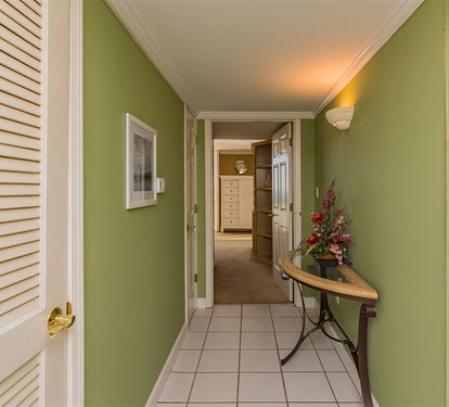 Step into your welcoming hallway where soothing green walls and warm lighting create an inviting path to your comfortable rooms.