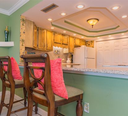 Your bright kitchen invites culinary adventures with granite counters, warm wood cabinets, and tropical charm.