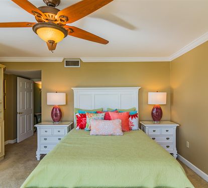 Unwind in your elegant bedroom featuring a comfortable bed, stylish fan, and built-in entertainment center for relaxing evenings.