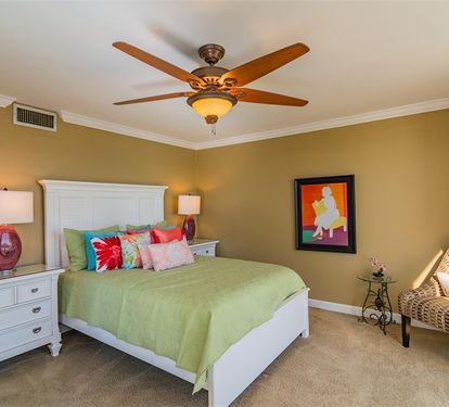 Unwind in your cozy bedroom with warm golden walls, fresh green linens, and tropical decor that creates the perfect retreat after busy days.