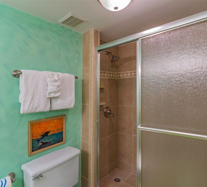 Your vibrant bathroom features calming turquoise walls and a spacious walk-in shower with elegant tiled walls, perfect for refreshing after beach days.