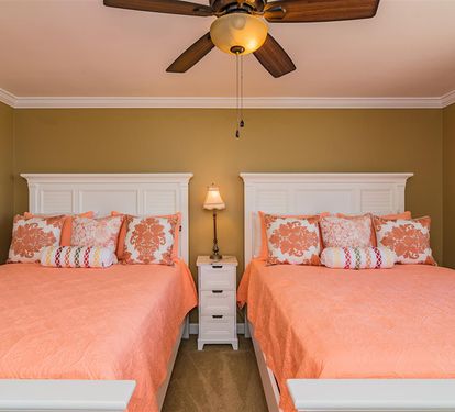 Rest peacefully in your cozy twin bedroom with cheerful coral bedding and warm lighting that creates the perfect atmosphere for a good night's sleep.
