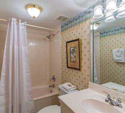 Step into your charming bathroom with tropical wallpaper and warm lighting that creates a cozy retreat for unwinding.