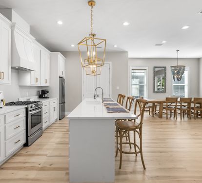 Your spacious open kitchen flows seamlessly into the dining area, where golden pendant lights illuminate meals shared around the expansive island.