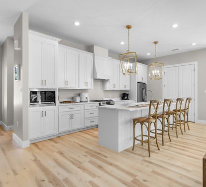 You'll love cooking in this bright, modern kitchen featuring pristine white cabinets, elegant brass pendant lights, and a spacious island perfect for gathering.