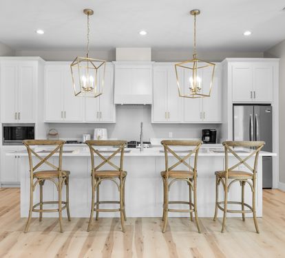 Your bright kitchen awaits with gleaming white cabinets, marble countertops, and cozy breakfast bar seating for four.