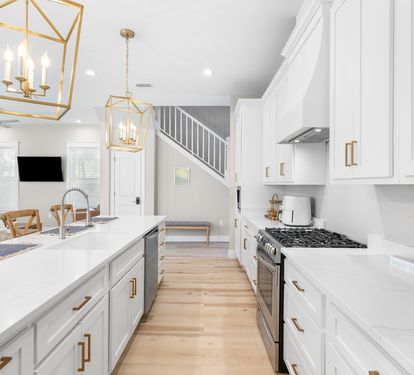 Your gourmet kitchen awaits with sleek white cabinets, gleaming countertops, and stylish brass fixtures that catch the light beautifully.
