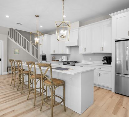 Step into your bright, modern kitchen where gleaming white cabinets and elegant pendant lighting create the perfect space for morning coffee and memorable meals together.