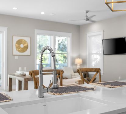 Your modern kitchen island flows seamlessly into a bright living space, where warm wood accents and natural light create the perfect gathering spot for your getaway.