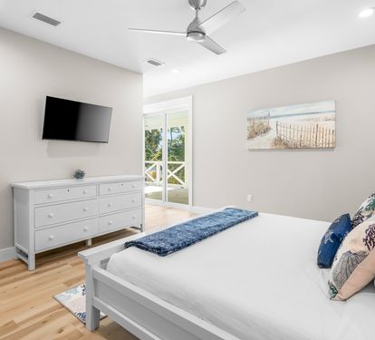 Drift off in this serene coastal bedroom with crisp linens, warm wood floors, and gentle ocean breezes from your private balcony.