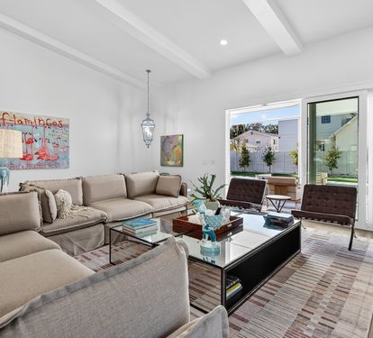 Sink into plush sofas beneath soaring beam ceilings in your bright, modern living space with floor-to-ceiling windows.