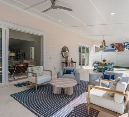 Relax in your covered outdoor living room with plush seating and ceiling fan for perfect comfort.