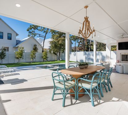 Your elegant covered patio flows seamlessly to the pool, where chandelier dining and cozy seating create perfect indoor-outdoor entertaining.