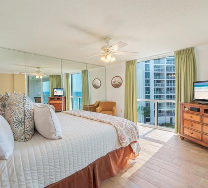 Wake up in your spacious bedroom with plush bedding and floor-to-ceiling windows revealing stunning city and ocean views.