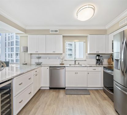 Your modern kitchen gleams with white cabinets and stainless steel appliances, while city views through bright windows inspire your culinary adventures.