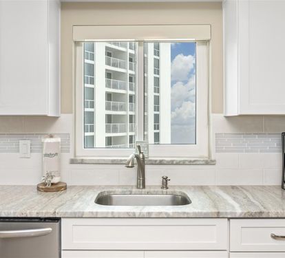 Start your morning routine in this bright, modern kitchen where granite counters and city views create the perfect coffee corner.